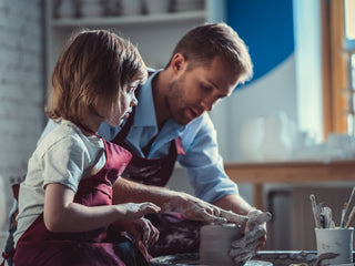 A man and daughter practicing guidance from the Hobby Toolbox to work on a pottery project together.