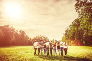 A group of friends embrace each other in a park and practice habits taught in the Friends Toolbox.